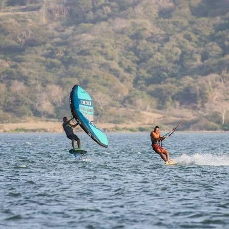 Un practicante de wing foil sobre hidroala y un kitesurfista navegando juntos en las aguas de Puerto Velero