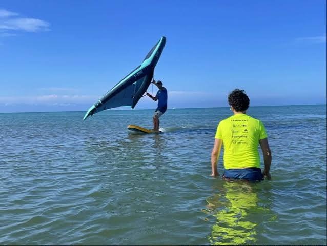 Un instructor demuestra wing foil mientras un estudiante observa desde el agua en Puerto Velero